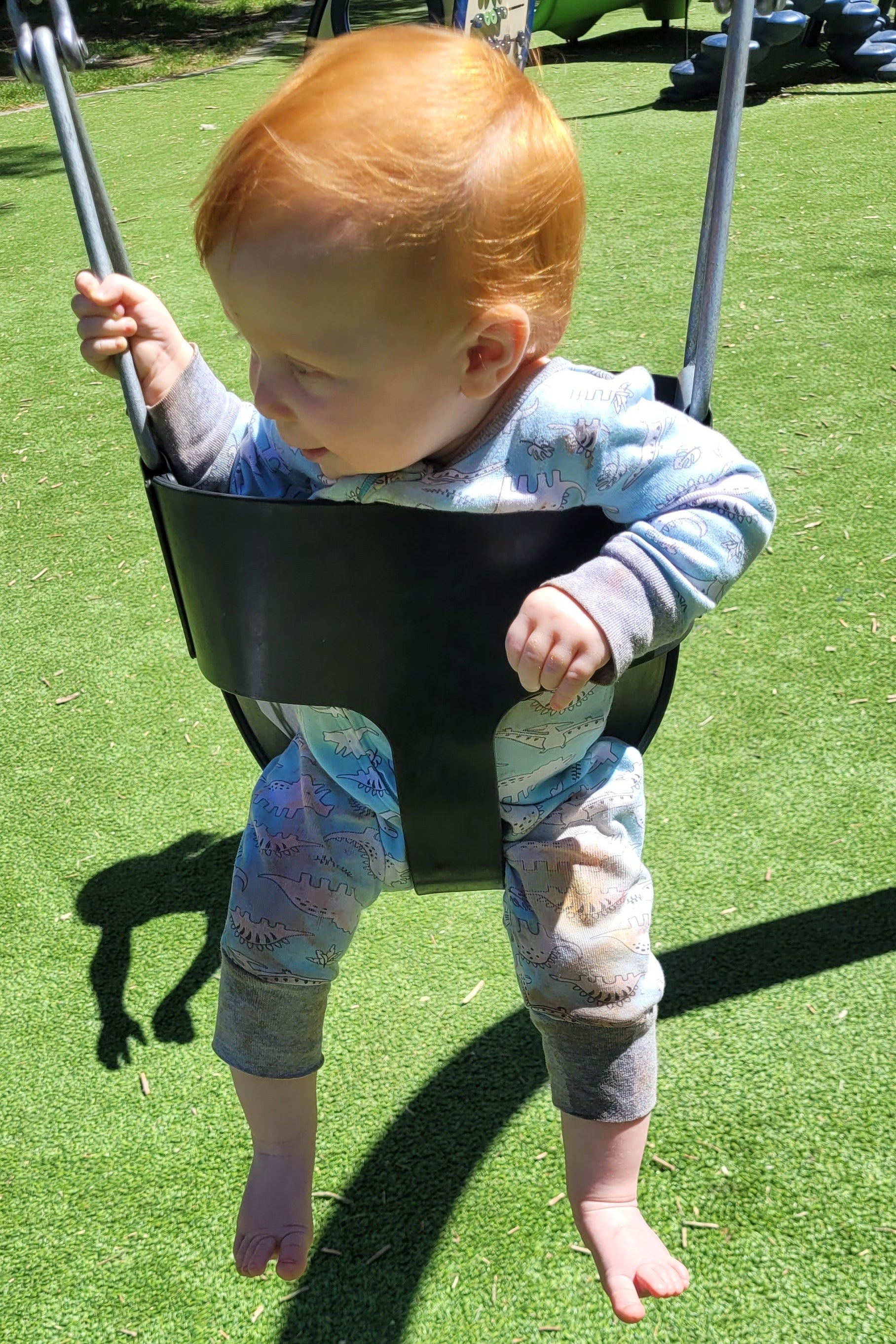 Child on a swing at a playground with grassy area