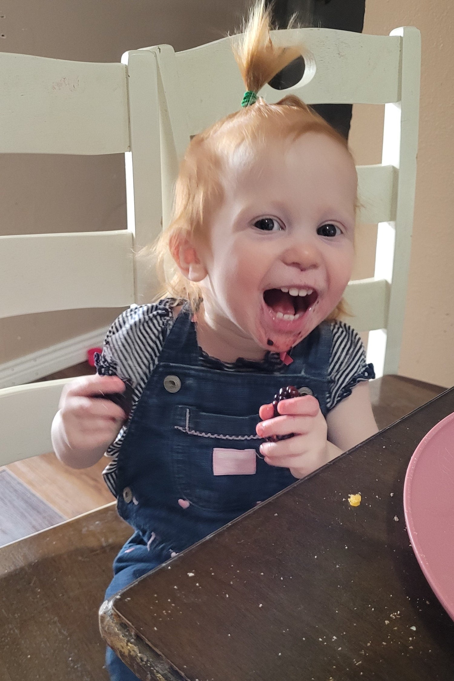 Child sitting on a chair with a surprised expression indoors