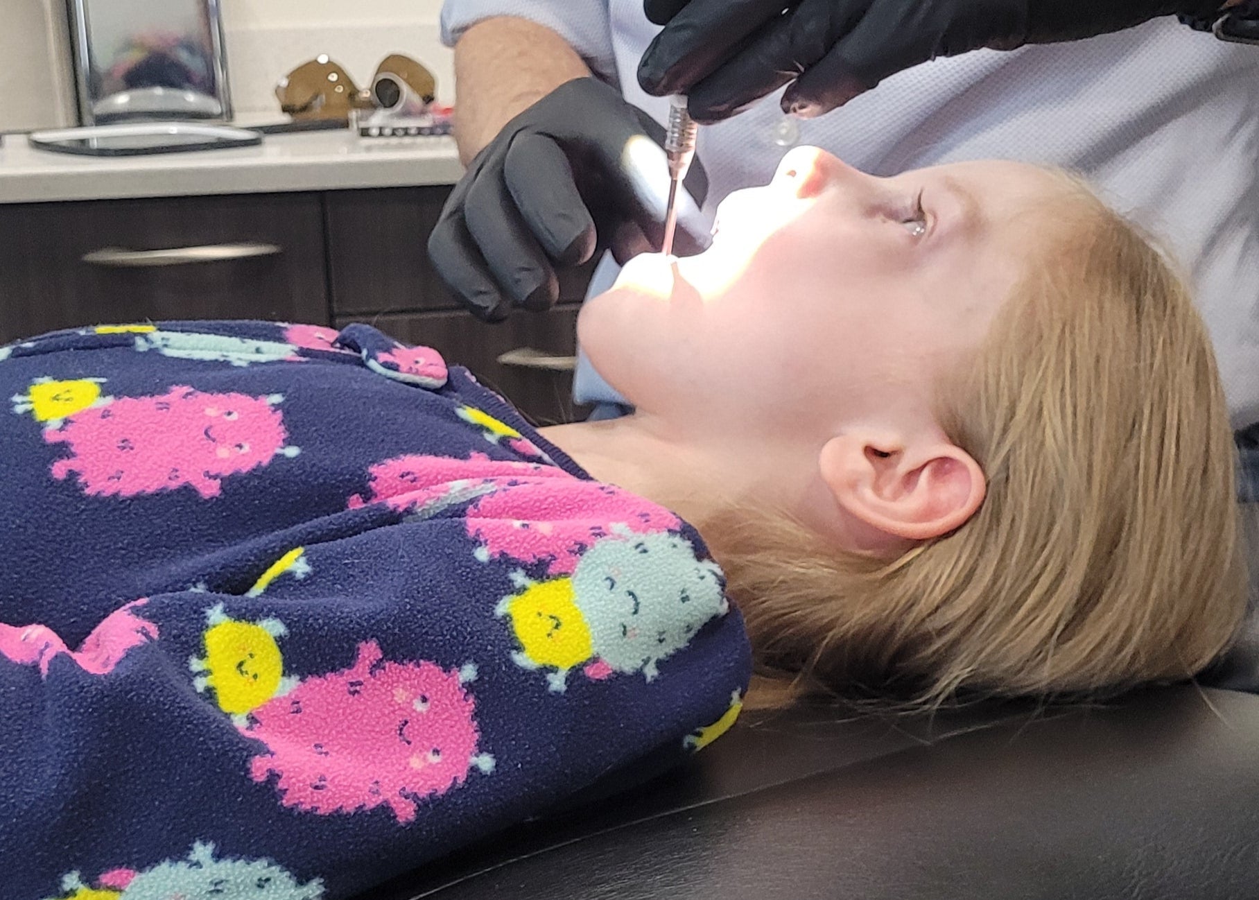 Child in dental chair with dentist examining teeth