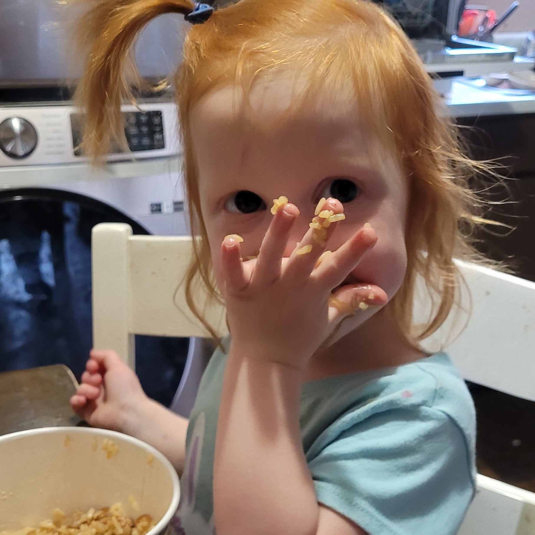 red haired toddler with rice on her hands
