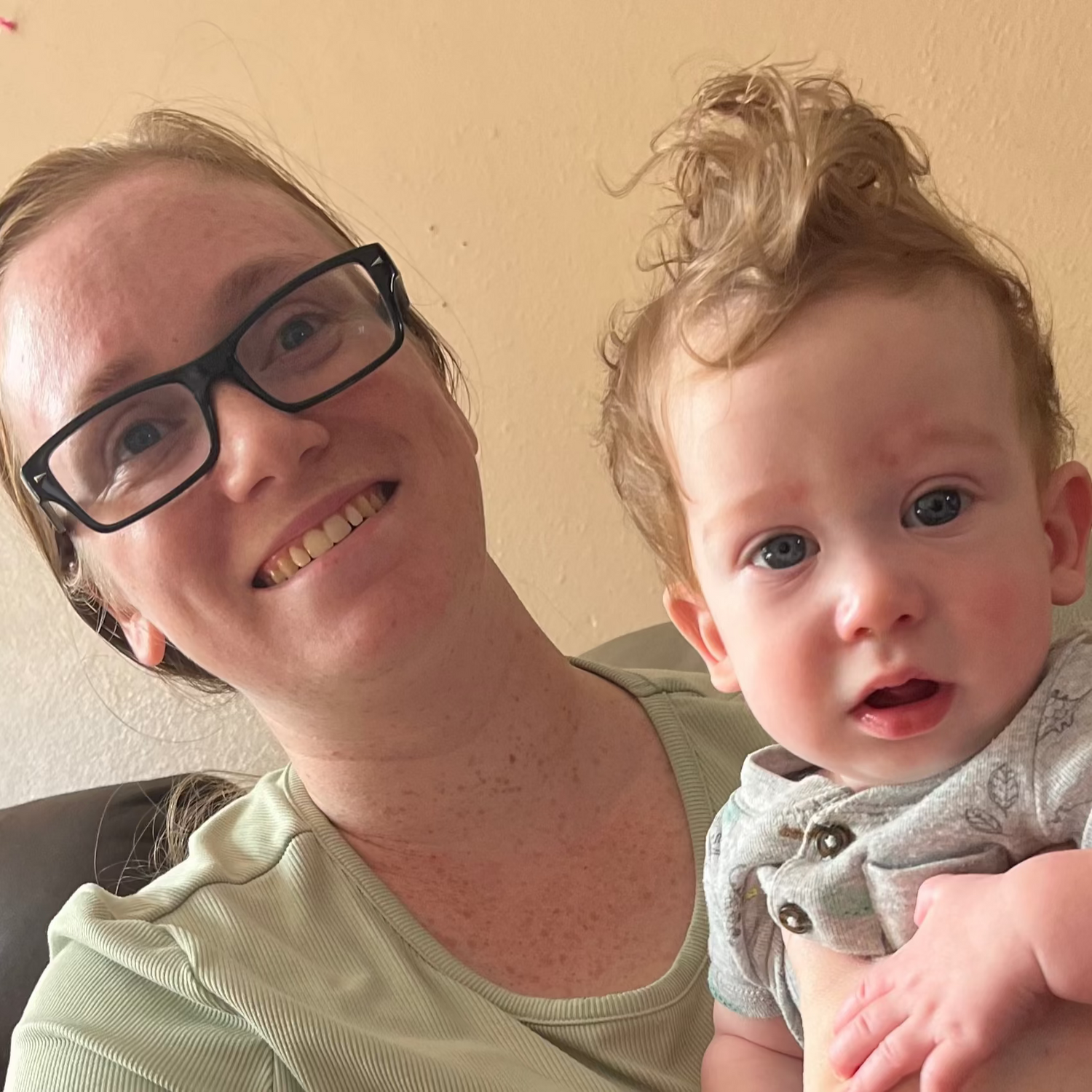 Woman holding a baby on a couch in a home setting
