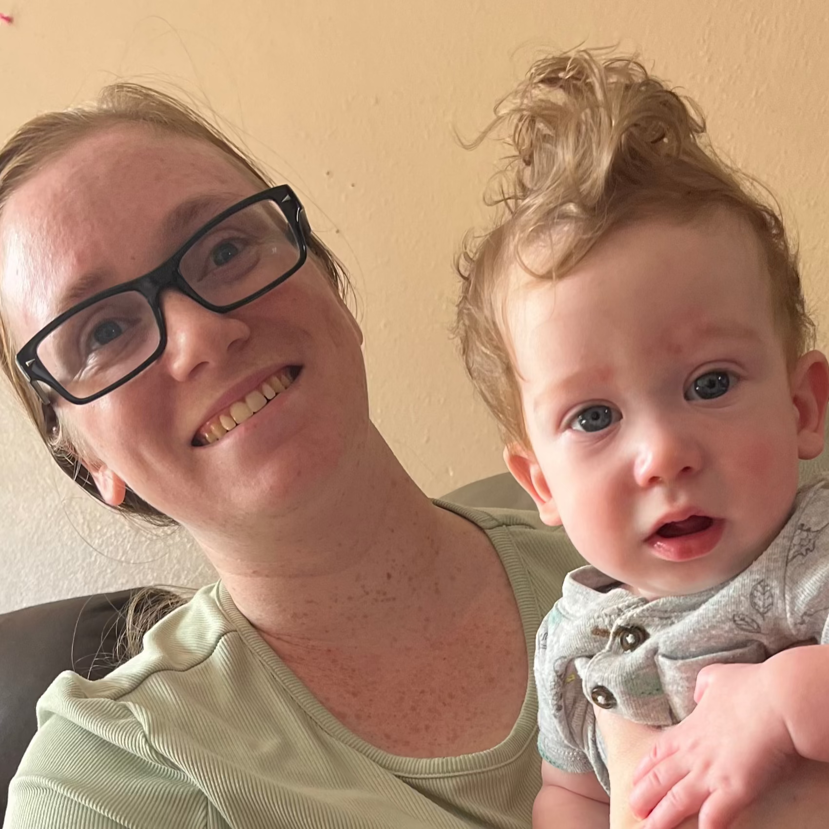 Woman holding a baby on a couch in a home setting